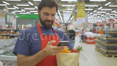 微笑<strong>超市</strong>员工使用手机，拿着购物袋在<strong>超市</strong>